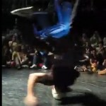 blurred action photo of young man spinning on head with blue plastic chair