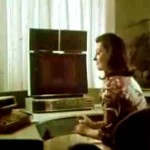 Woman with long hair sitting in front of video screens