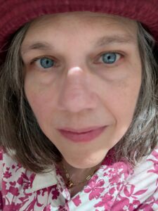 Portrait of Alice in burgundy hate and pink and white flowered shirt